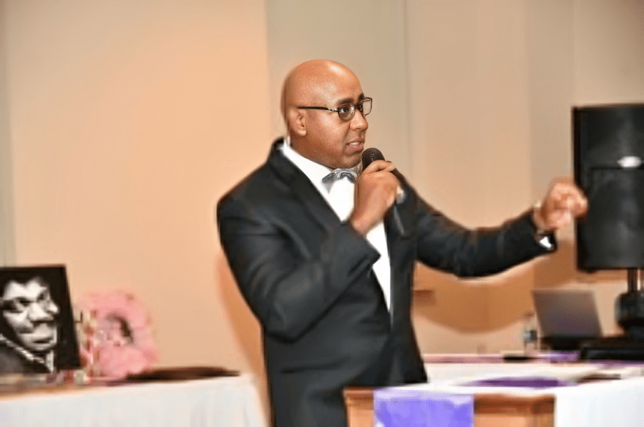 Man in suit speaking at an event.